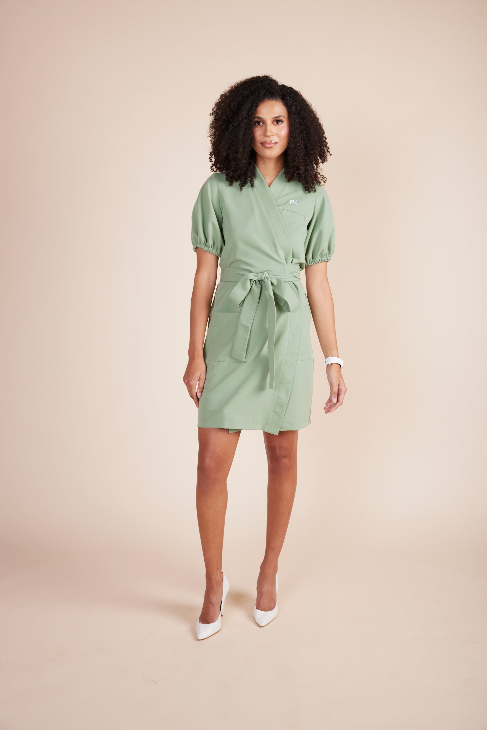 Mary Scrub Dress in Green Tea by DUES – luxury scrub dress sewn in the USA, featuring a flattering silhouette, breathable stretch fabric, and functional design details for comfort and mobility during long shifts.