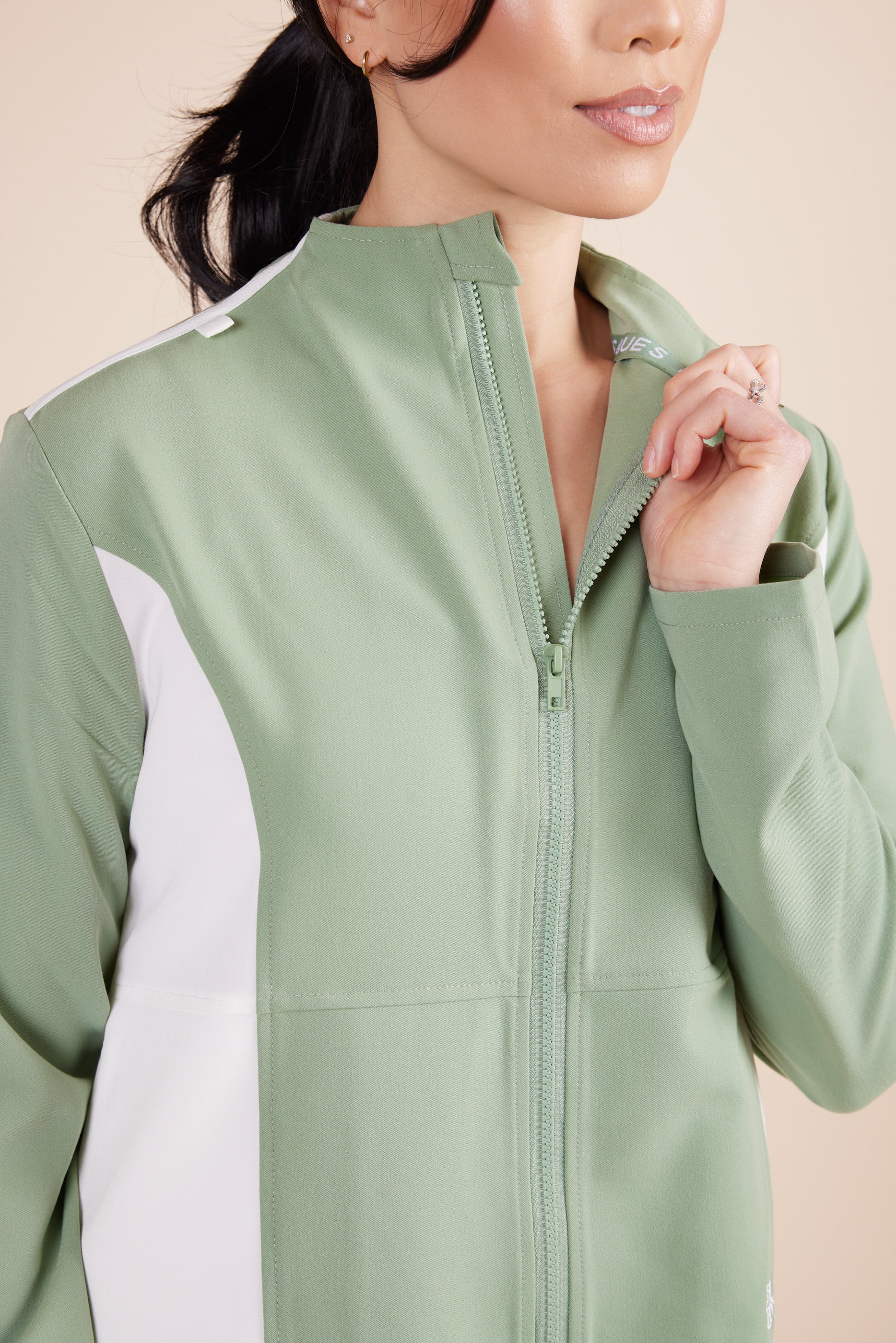 Jade Jacket in Green Tea by DUES – luxury zip-up scrub jacket sewn in the USA, featuring contrast white side panels, a sleek high collar, and modern tailoring for a polished, functional fit.
