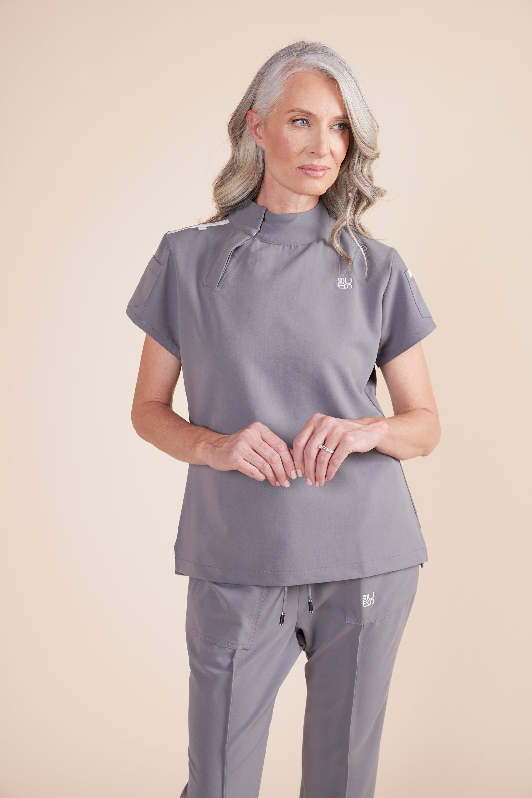 Jackie Scrub Top in Gray by DUES – luxury scrub top sewn in the USA, featuring contrast key loops, side splits, and high-stretch panels for comfort and mobility.