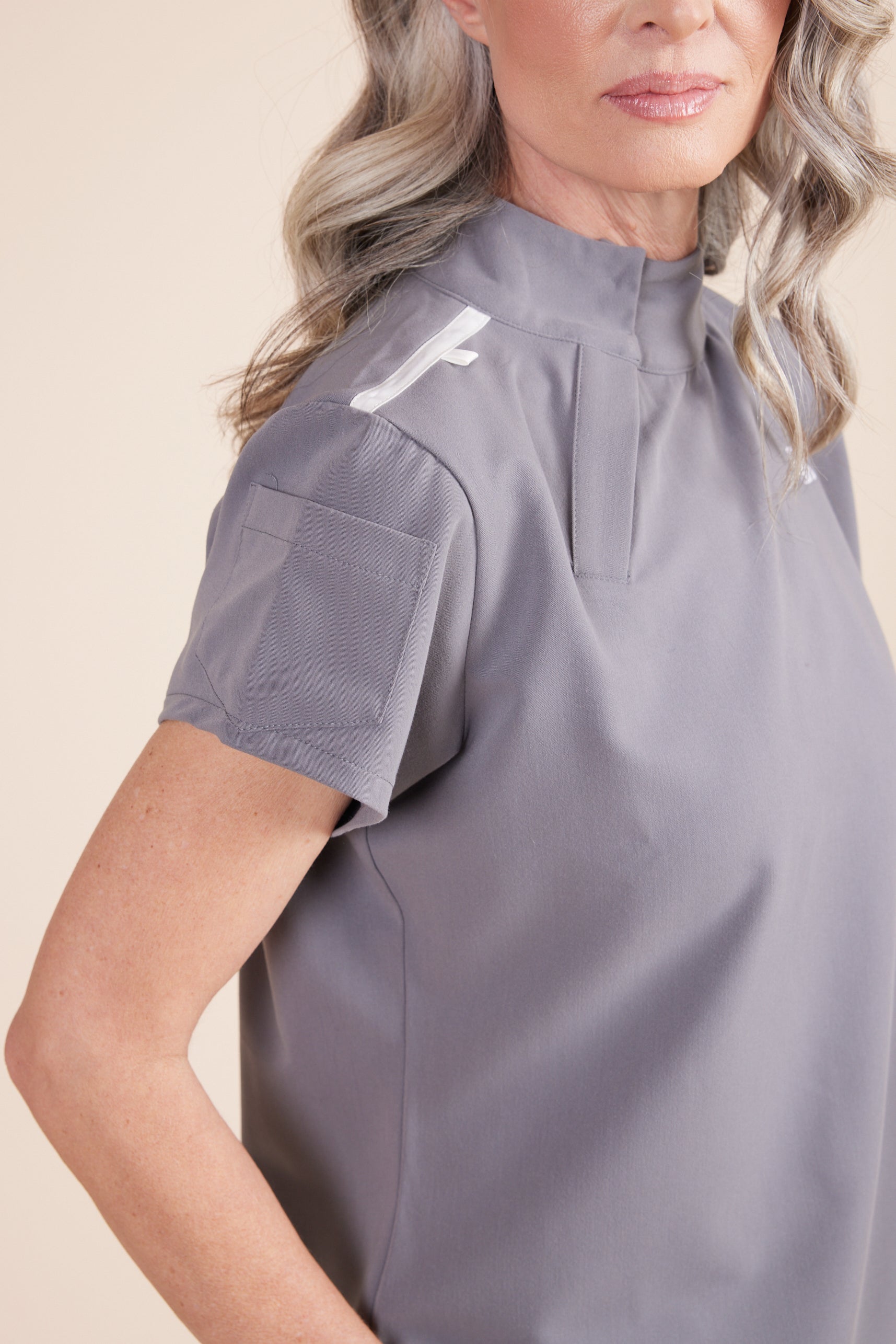 Jackie Scrub Top in Gray by DUES – luxury scrub top sewn in the USA, featuring contrast key loops, side splits, and high-stretch panels for comfort and mobility.