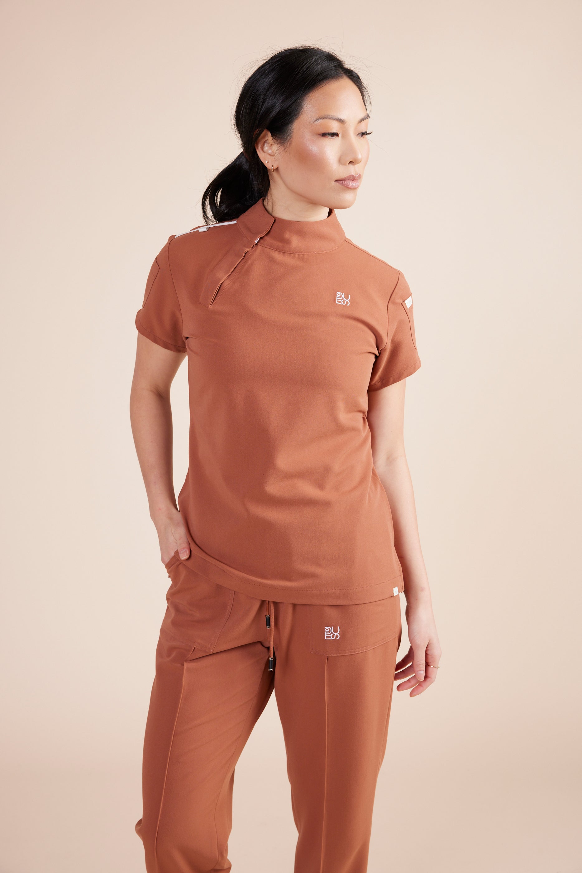Jackie Scrub Top in Terracotta by DUES – luxury scrub top sewn in the USA, featuring contrast key loops, side splits, and high-stretch panels for comfort and mobility.
