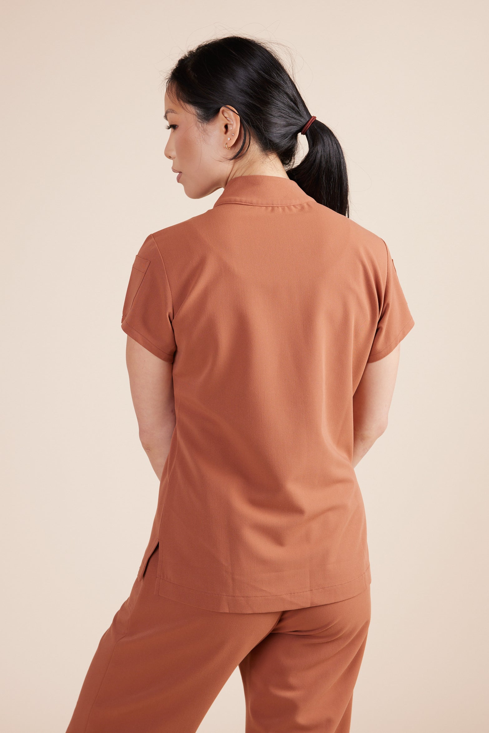 Jackie Scrub Top in Terracotta by DUES – luxury scrub top sewn in the USA, featuring contrast key loops, side splits, and high-stretch panels for comfort and mobility.
