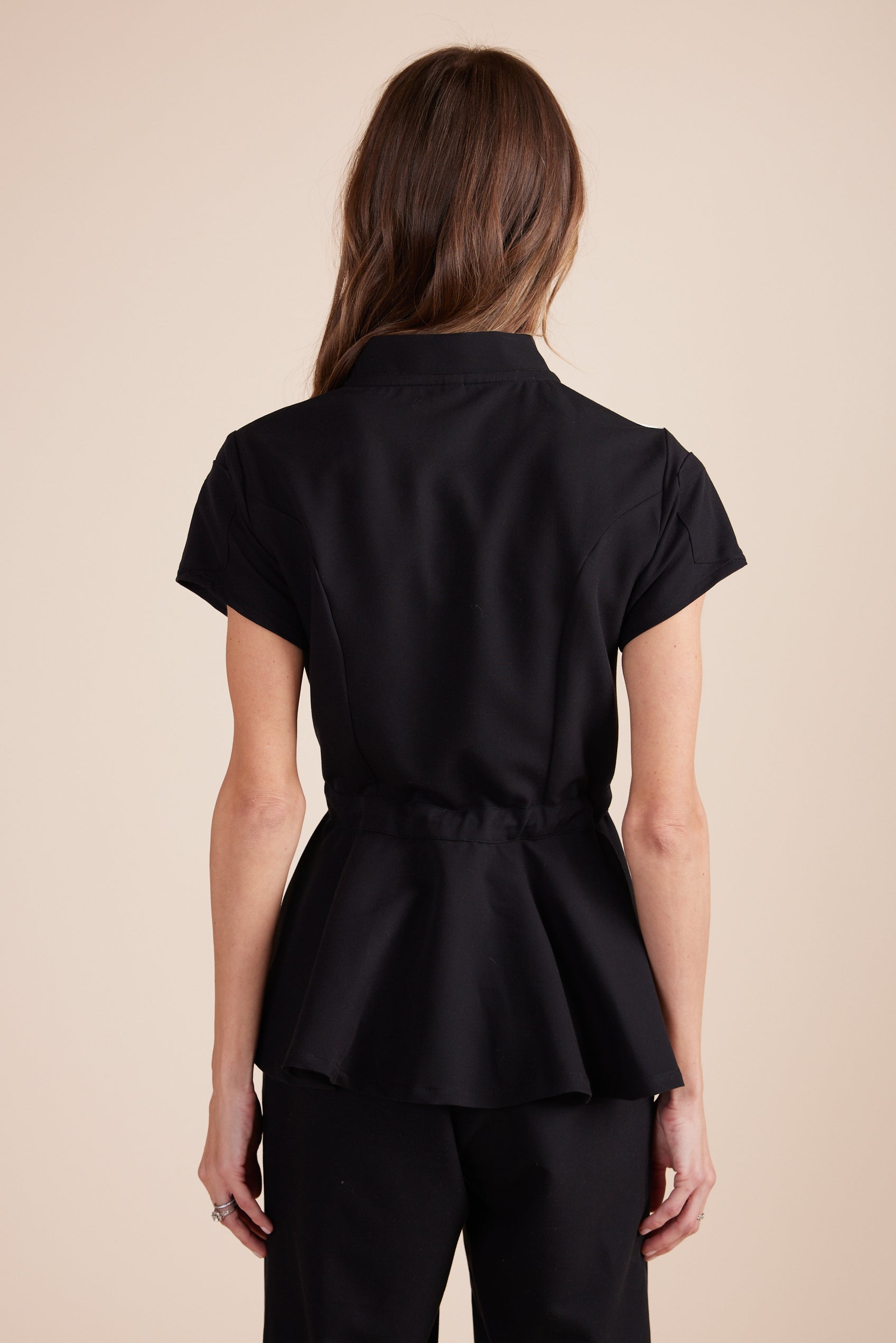 Deanna Scrub Top in Black by DUES – luxury scrub top sewn in the USA, featuring a cinched waist design, contrast key loops, side splits, and high-stretch panels for comfort and mobility.