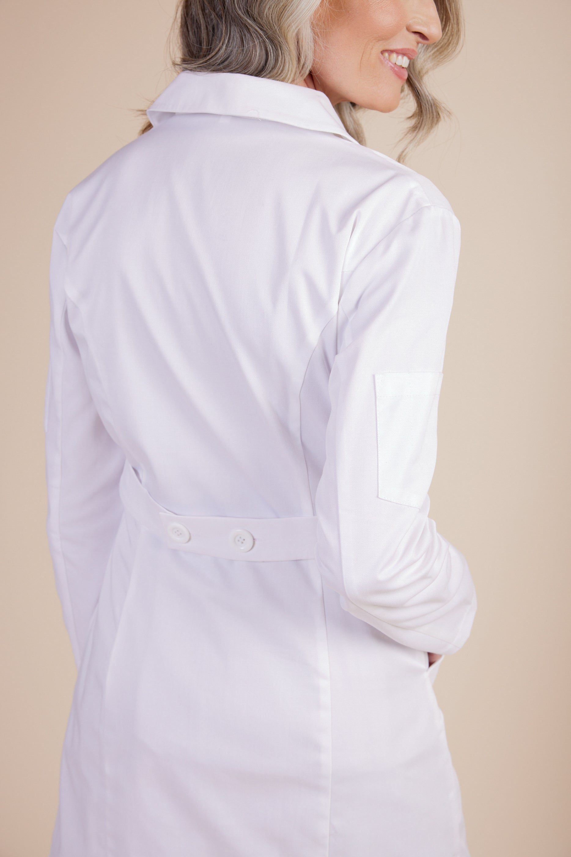 Rebecca Lab Coat in White by DUES – luxury lab coat sewn in the USA, featuring a tailored silhouette, double-button front closure, utility sleeve pocket, and spacious front patch pockets for elevated everyday function.