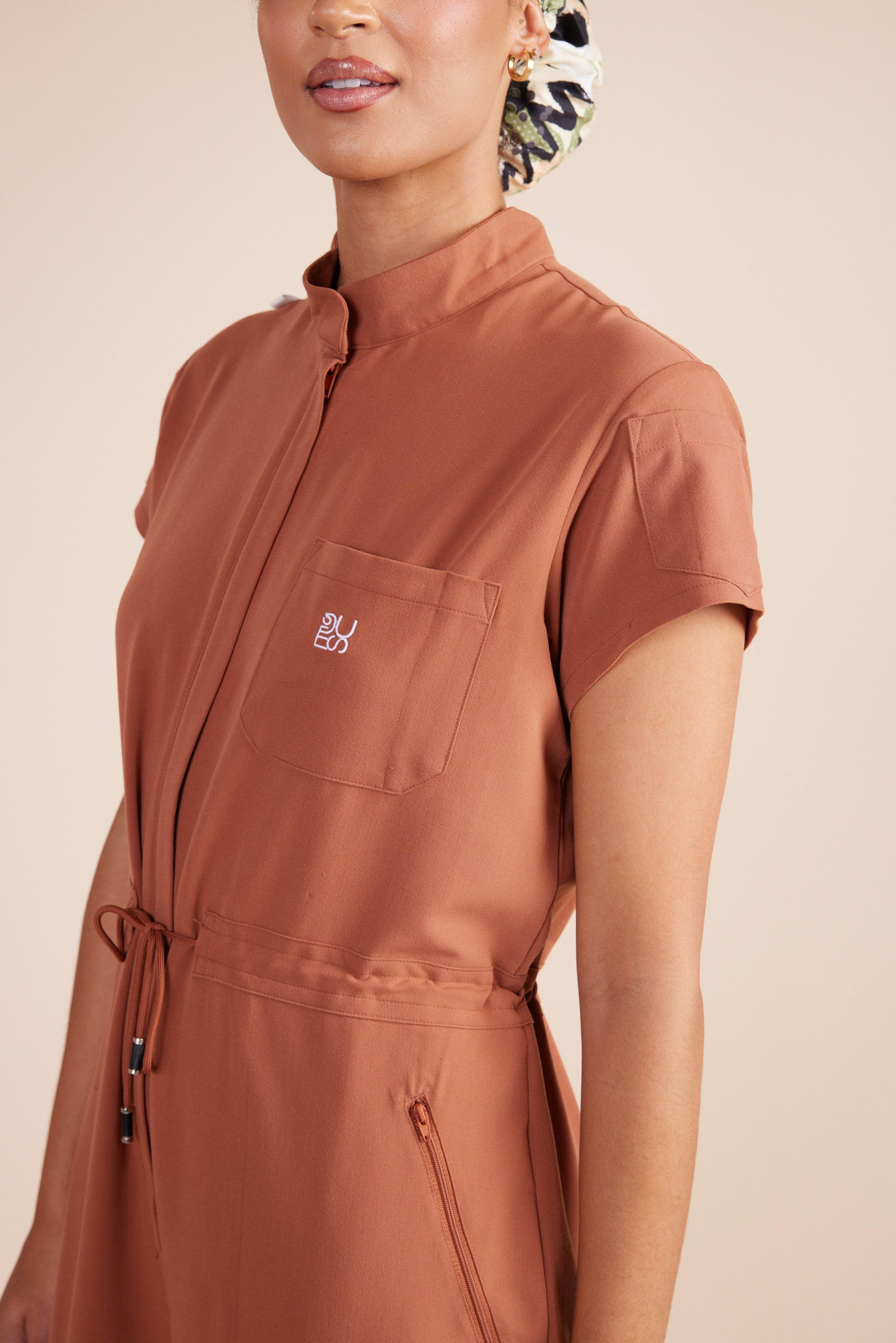 Ebony Scrub Jumpsuit in Terracotta by DUES – luxury scrub jumpsuit sewn in the USA, offering a polished one-piece design with breathable, high-performance fabric for ultimate comfort.