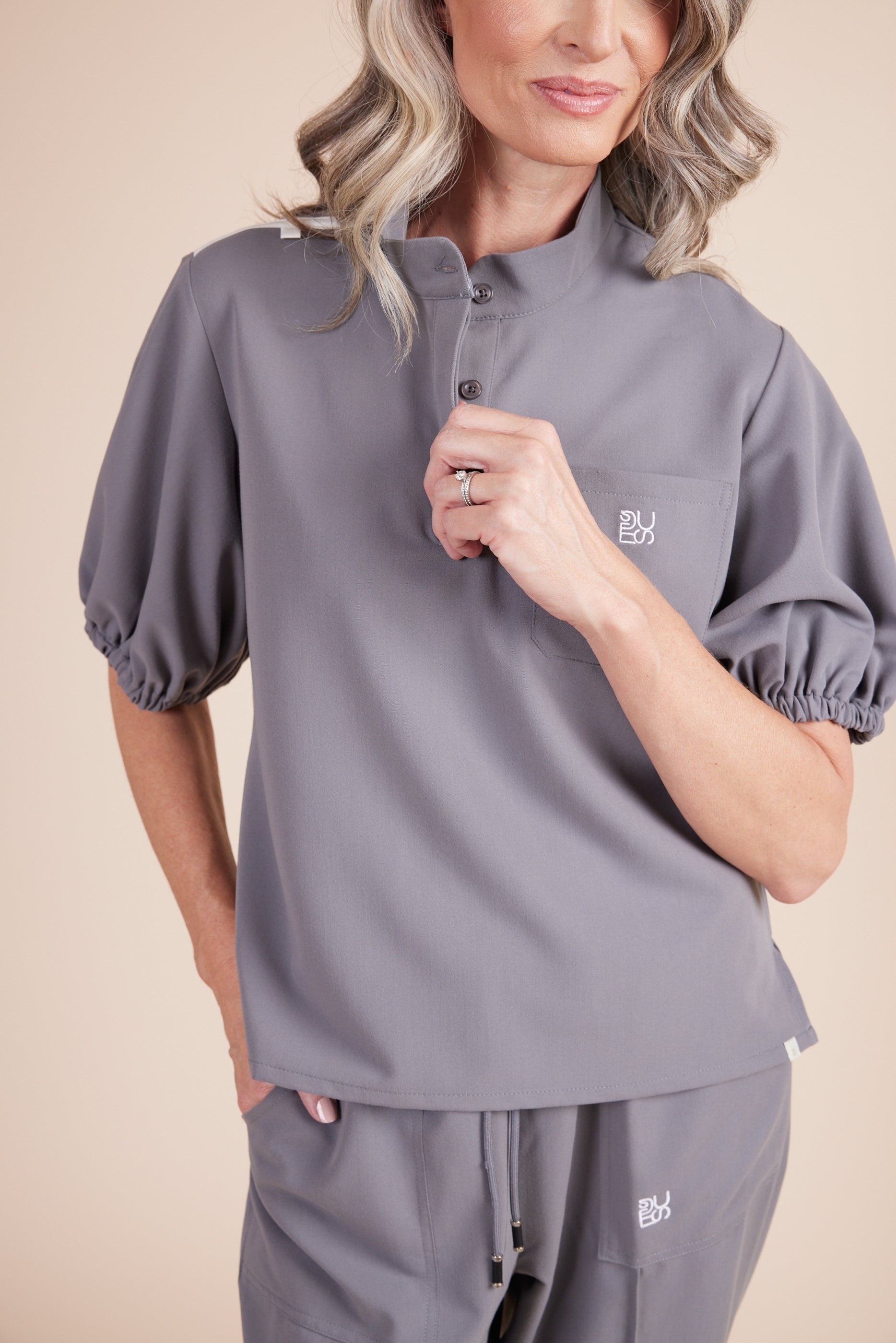 Helen Scrub Top in Gray by DUES – luxury scrub top sewn in the USA, featuring contrast key loops, side splits, and high-stretch panels for comfort and mobility.
